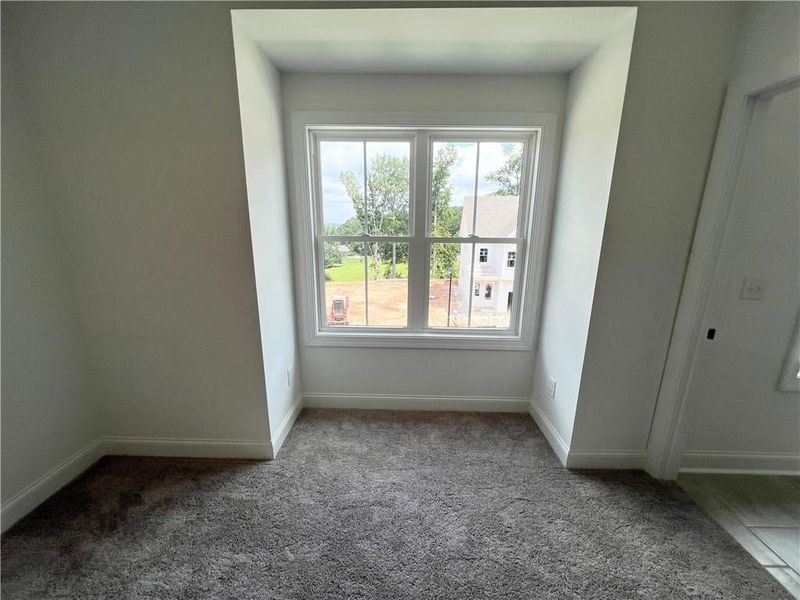 Bedroom #2  featuring carpet floors and baseboards and bump out for built in bench.