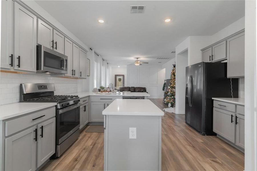 Kitchen with gray cabinetry, ceiling fan, a center island, and appliances with stainless steel finishes