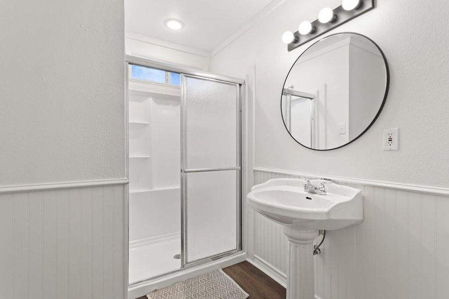 Full bathroom featuring wainscoting, a shower stall, and wood finished floors