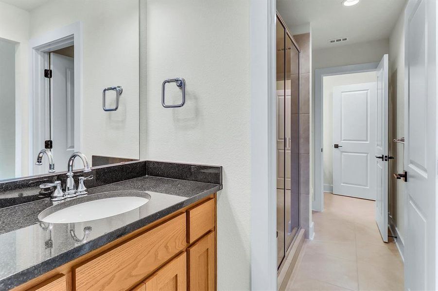 Bathroom vanity featuring a polished chrome faucet, an integrated oval sink, and a dark stone countertop Bathroom vanity featuring a polished chrome faucet, an integrated oval sink, and a dark stone countertop