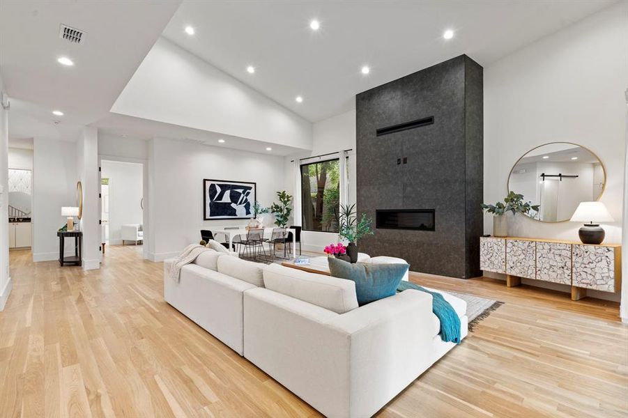 Living area featuring high vaulted ceiling, light wood-style floors, recessed lighting, and a tile fireplace Living area featuring high vaulted ceiling, light wood-style floors, recessed lighting, and a tile fireplace