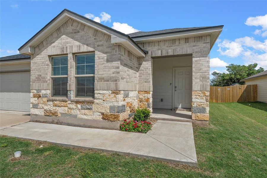 View of exterior entry featuring stone siding and an attached garage View of exterior entry featuring stone siding and an attached garage