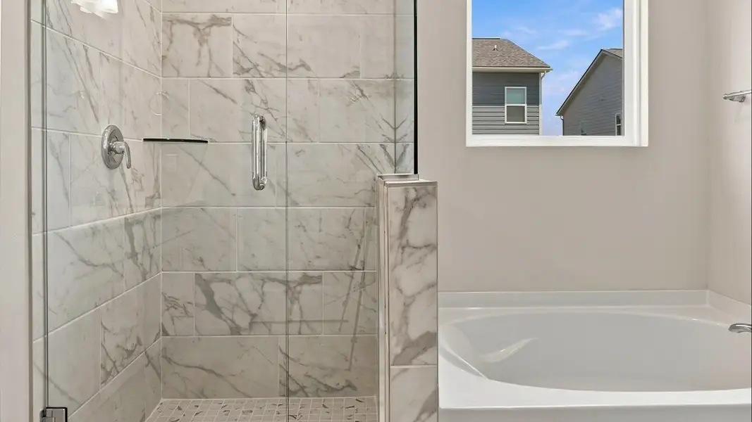 Tiled shower and separate soaking tub in primary suite Tiled shower and separate soaking tub in primary suite
