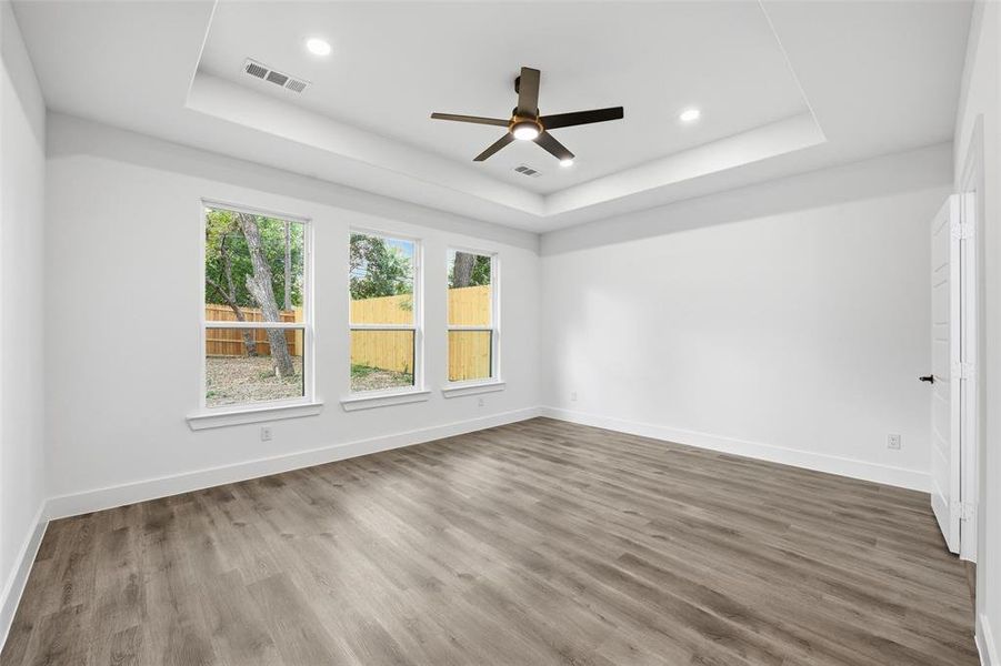 Spare room with a raised ceiling, wood finished floors, ceiling fan, and recessed lighting