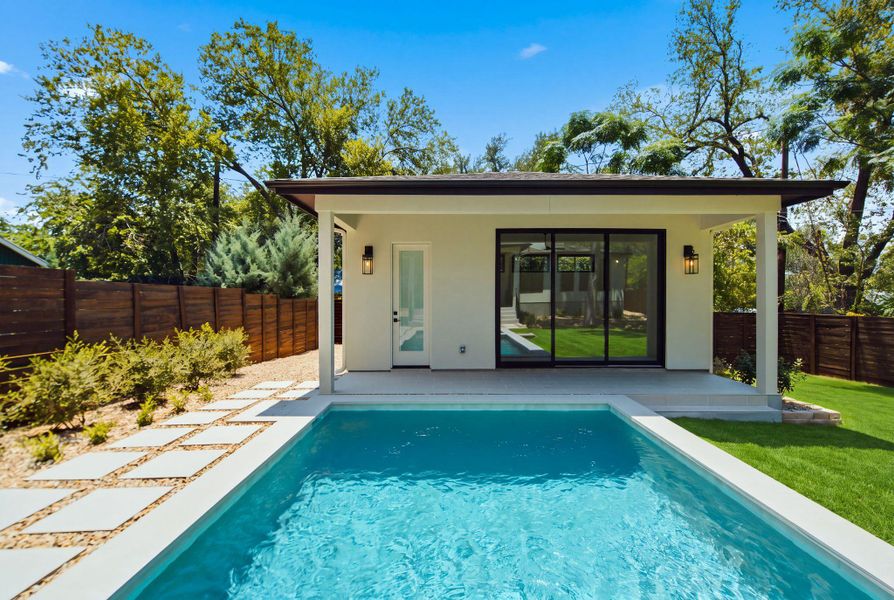 An inviting backyard oasis features a shimmering swimming pool alongside a modern pool house.