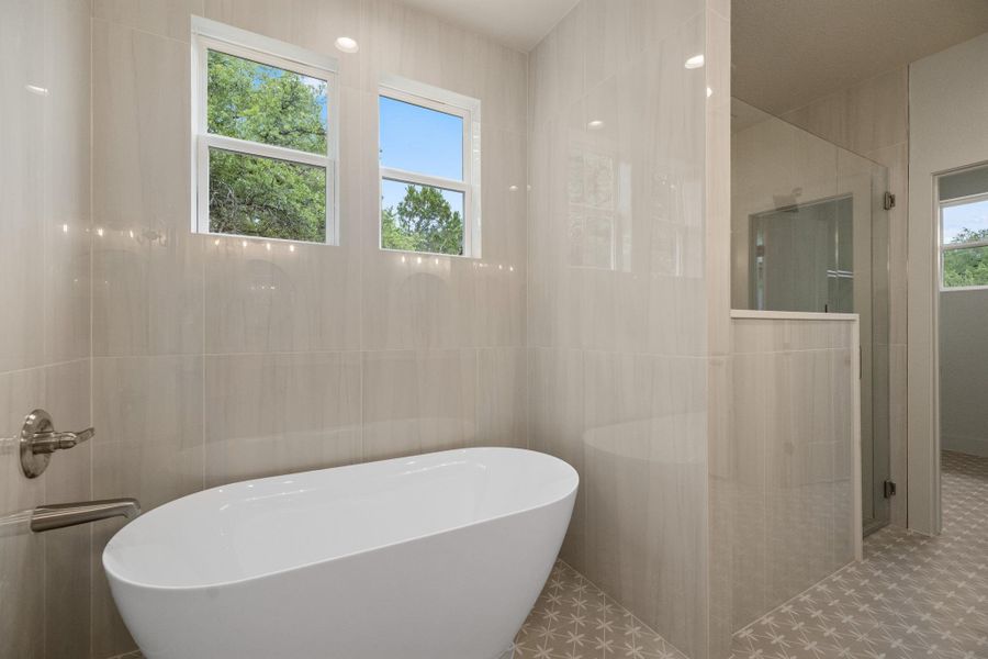 A modern bathroom showcasing a deep soaking tub and a spacious glass-enclosed shower.