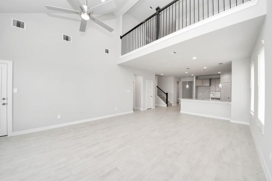 Bring your loved ones and guests together in the inviting living room! Boasting lofty high ceilings, recessed lighting, a stylish ceiling fan, custom paint, stunning flooring, and expansive windows that flood the space with ample natural light all day long. Sample photo of completed home with similar floor plan. Actual colors and selections may vary.