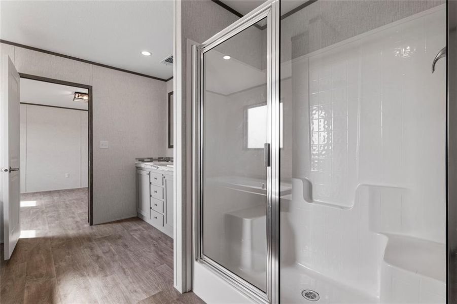 Bathroom featuring a shower stall, vanity, light wood-style floors, crown molding, and recessed lighting
