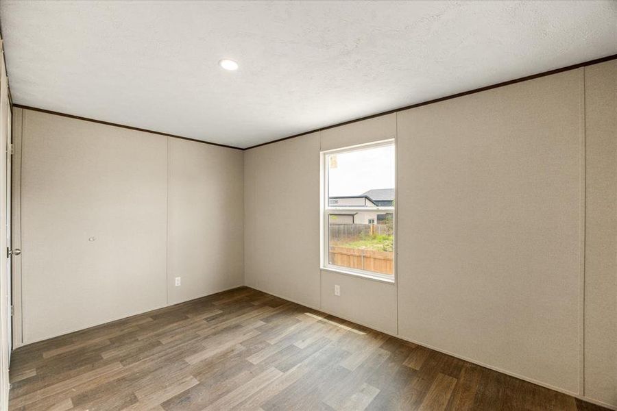 Room featuring wood-finish flooring, recessed ceiling lighting, and a single window with a white frame