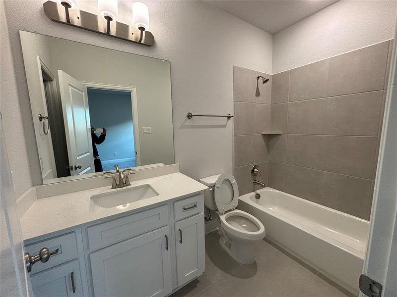 Full bathroom with toilet, tiled shower / bath, vanity, and tile patterned floors