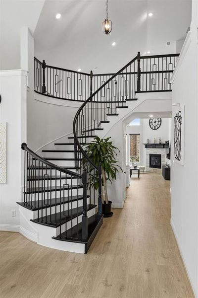 Grand curved staircase featuring black treads and custom iron balusters