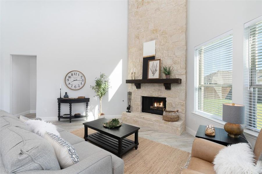 Living room featuring a fireplace, a towering ceiling, and light hardwood / wood-style flooring