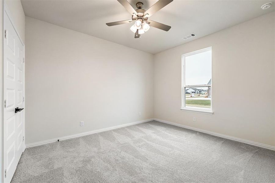 Empty room with light carpet and a ceiling fan