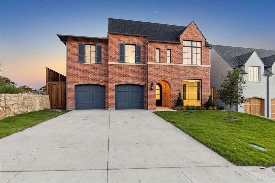 View of front of property featuring a garage and a yard