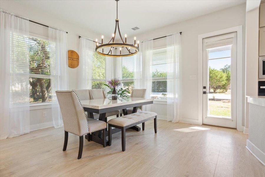 Dining room with light wood finished floors and designer hanging lights