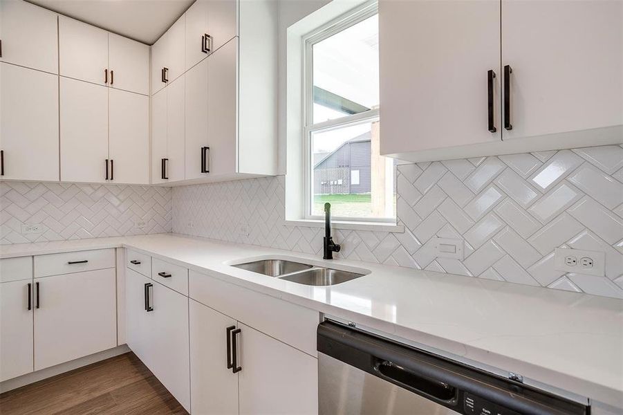 Kitchen with white cabinetry, decorative backsplash, dark wood-type flooring, dishwasher, and sink Kitchen with white cabinetry, decorative backsplash, dark wood-type flooring, dishwasher, and sink