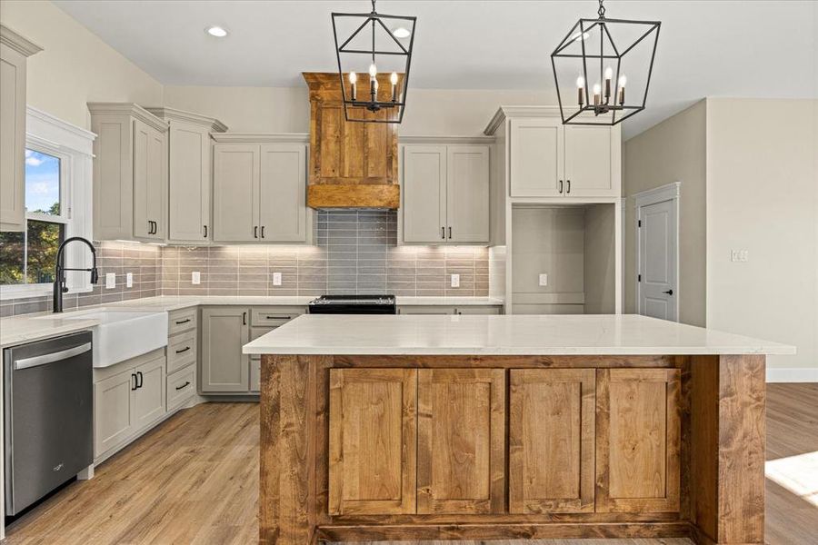 Kitchen featuring a kitchen island, light wood-style floors, backsplash, stainless steel appliances, and quartz countertops