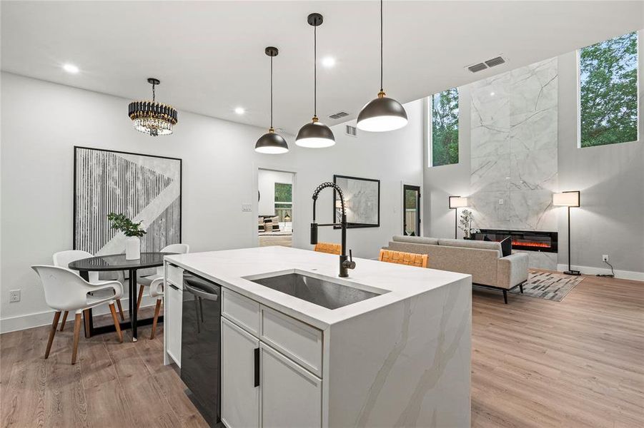 Kitchen featuring light wood-type flooring, decorative light fixtures, and white cabinets