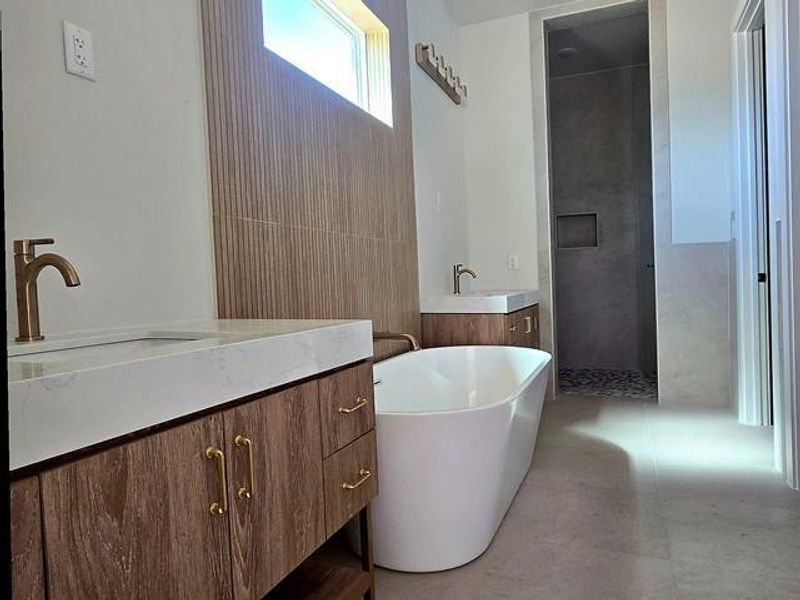 Full bath featuring vanity, a freestanding tub, walk in shower, and concrete flooring