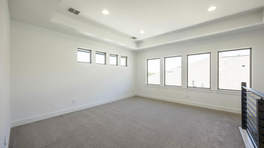 Spare room featuring a raised ceiling, light carpet, and recessed lighting