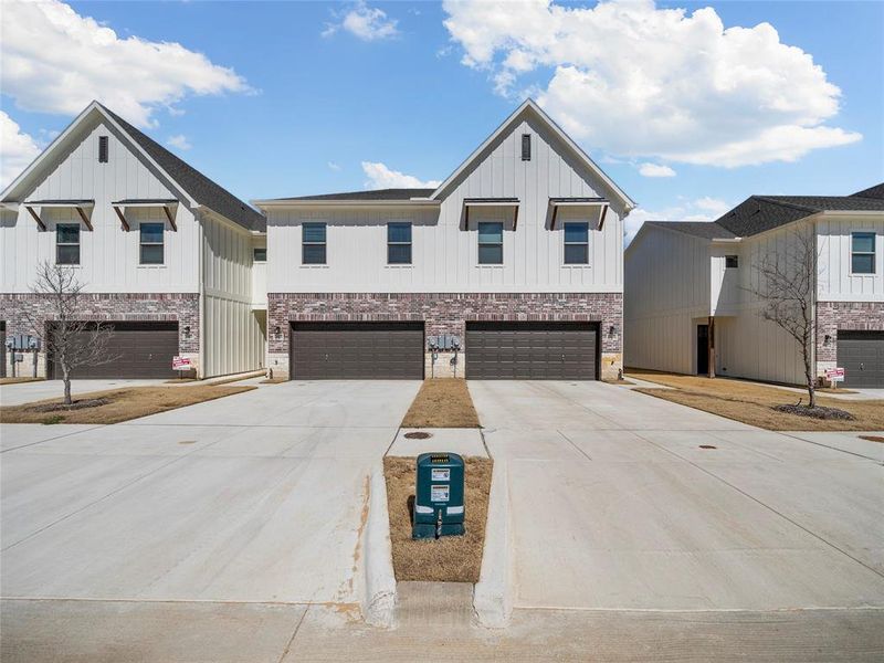 Modern farmhouse with a garage, driveway, brick siding, and board and batten siding