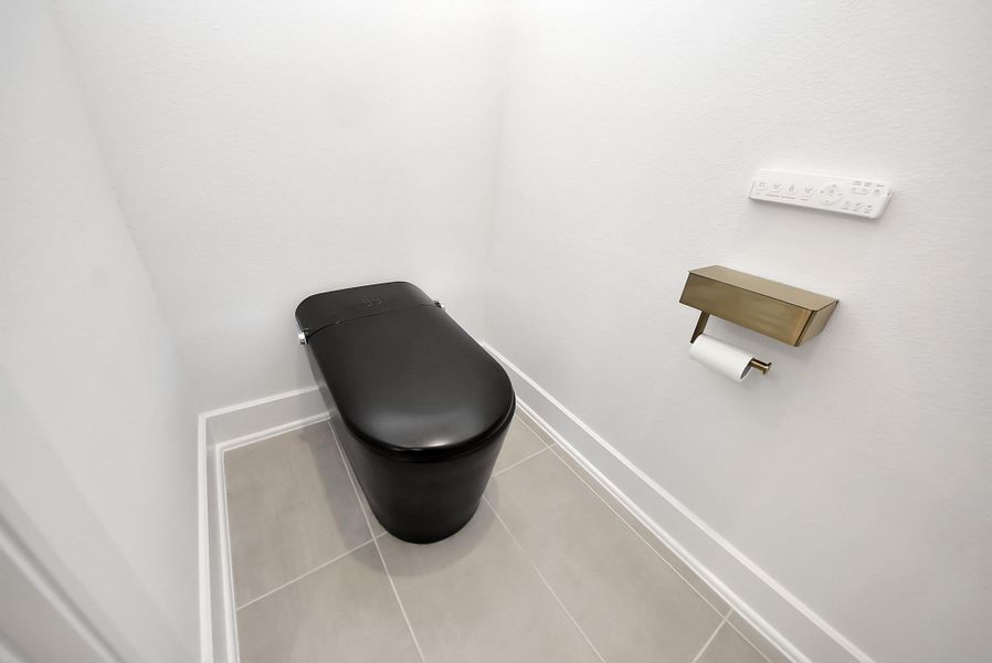 Private water closet featuring a modern smart toilet and sleek gold accents.
