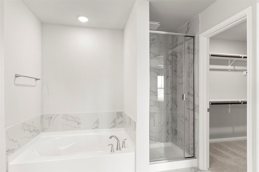 Full bath with a walk in closet, a marble finish shower, and a garden tub