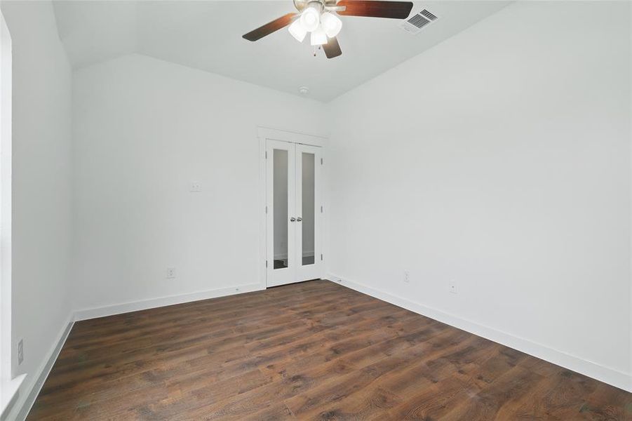 Empty room with dark wood-type flooring, french doors, lofted ceiling, and a ceiling fan Empty room with dark wood-type flooring, french doors, lofted ceiling, and a ceiling fan