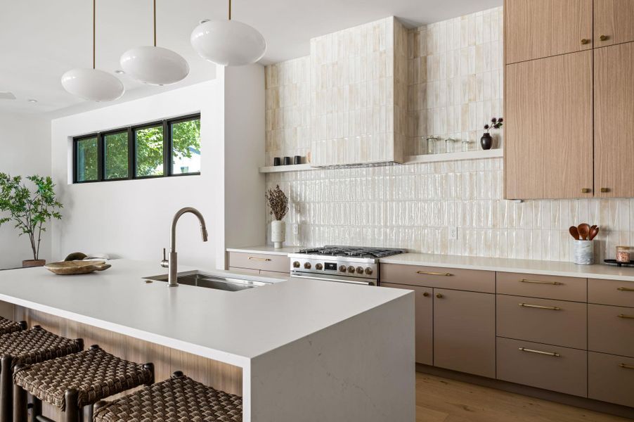 Gleaming stone countertops and a vertical tile backsplash define this modern cooking space.