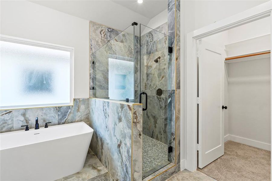 Bathroom featuring a marble finish shower, a soaking tub, and tile walls Bathroom featuring a marble finish shower, a soaking tub, and tile walls