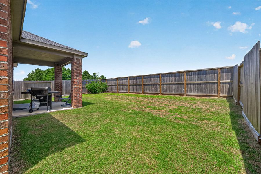 Spacious backyard with a covered patio, perfect for outdoor entertaining and relaxation.