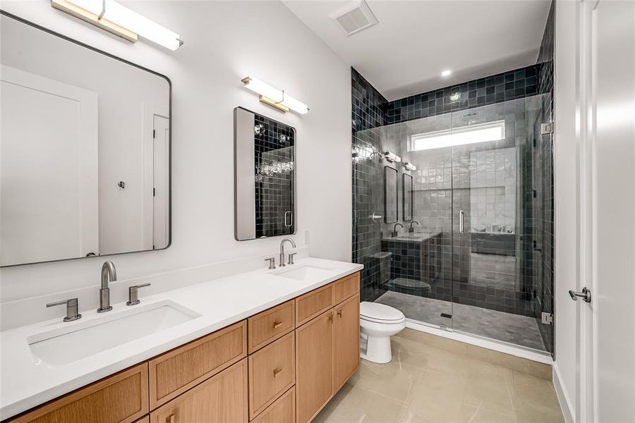 Spacious bathroom featuring a dual vanity with wood-finish cabinetry, white countertops, and matte chrome fixtures