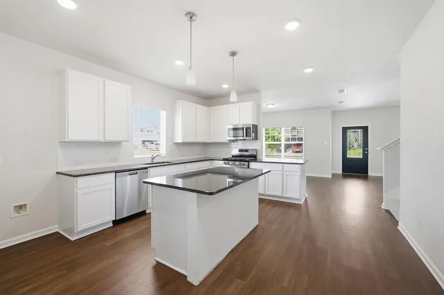 Modern kitchen featuring white cabinetry, dark countertops, a central island, recessed lighting, and stainless steel appliances