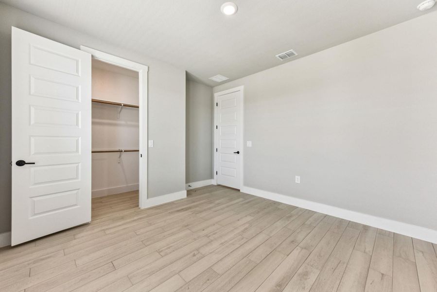 Unfurnished bedroom featuring a spacious closet, light wood-style floors, and recessed lighting