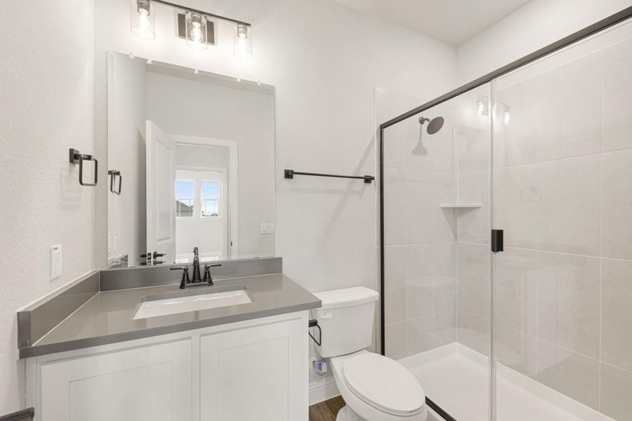 Bathroom with white vanity, gray countertop, glass walk-in shower, and black fixtures
