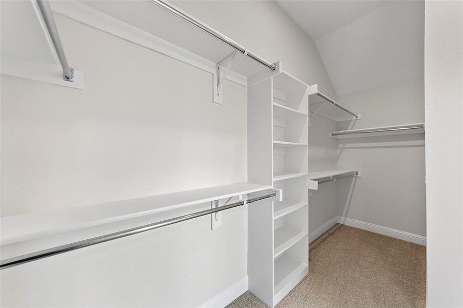 Walk in closet featuring light carpet and vaulted ceiling