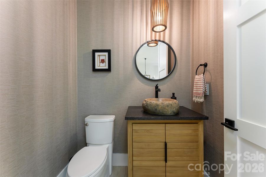 1/2 bath on main level boasts a stone vessel sink and gorgeous wallpaper