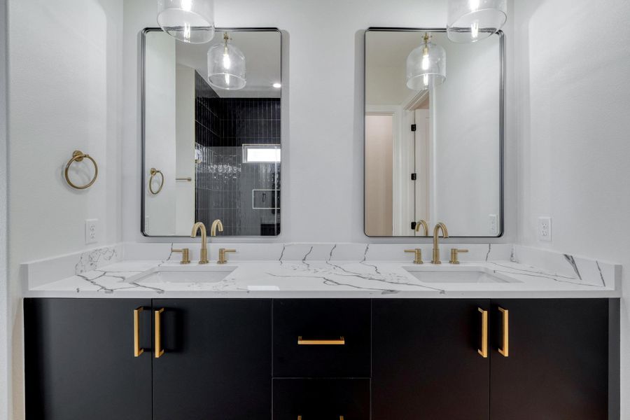 Full bathroom featuring double vanity, tiled shower, and a sink