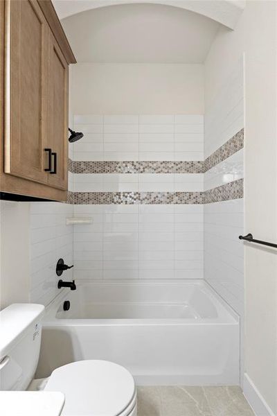 Bathroom with tiled shower / bath and toilet