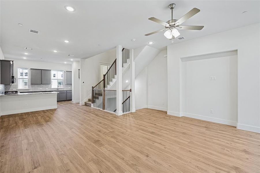 Unfurnished living room with light wood-style flooring, ceiling fan, recessed lighting, and stairs