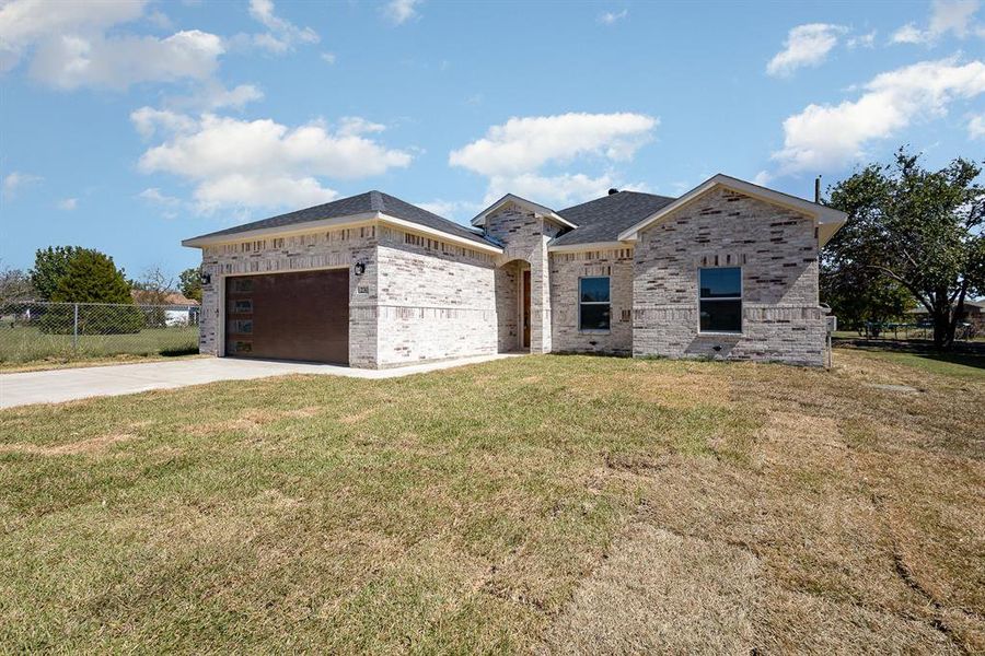 View of front of house with a garage, fence, brick siding, a front lawn, and driveway