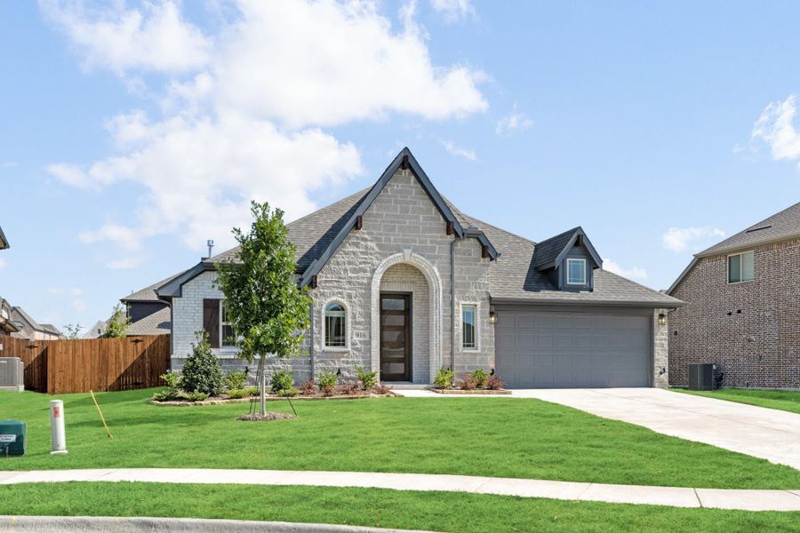 Single-story home with light stone exterior, arched entry, two-car garage, and manicured front lawn