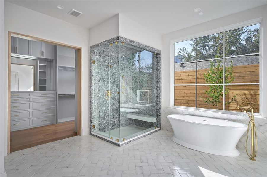 Designed for ultimate relaxation, the ensuite bathroom boasts a frameless, glass-enclosed shower with a built-in bench, offering a sleek and modern aesthetic. Adjacent to it, the Maidstone Julian pedestal soaking tub serves as a luxurious focal point, perfect for unwinding. Both feature elegant Waterworks plumbing fixtures, enhancing the space with timeless sophistication.