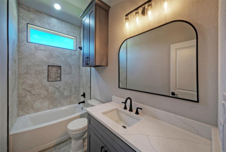 Tiled walls and a sleek vanity cabinet elevate this contemporary bathroom space. Tiled walls and a sleek vanity cabinet elevate this contemporary bathroom space.