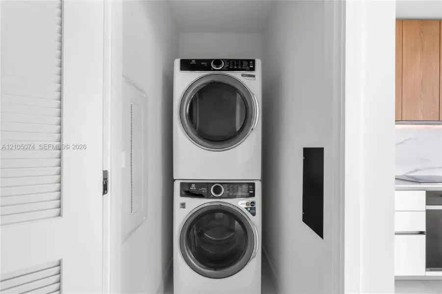 Stacked front-load washer and dryer unit, louvered closet door, and electrical panel access