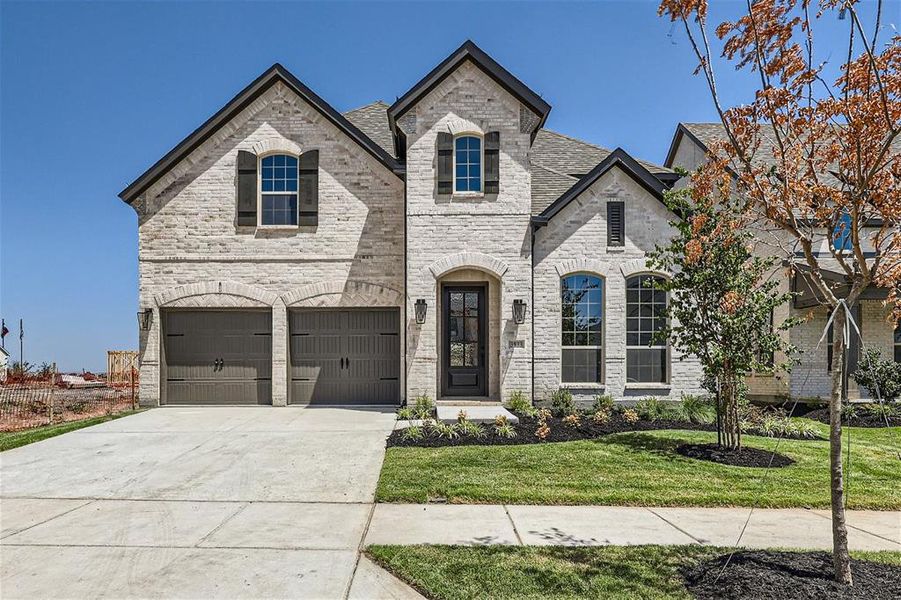 French provincial home featuring a garage and a front lawn