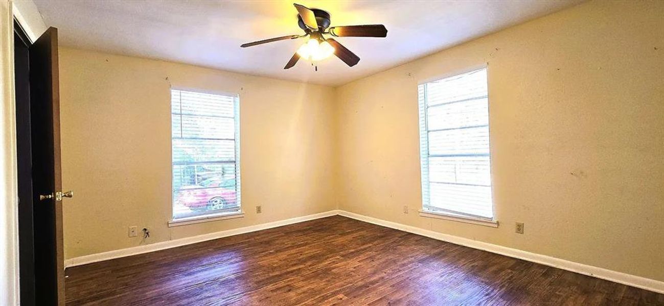 Unfurnished room featuring dark wood-style flooring and ceiling fan