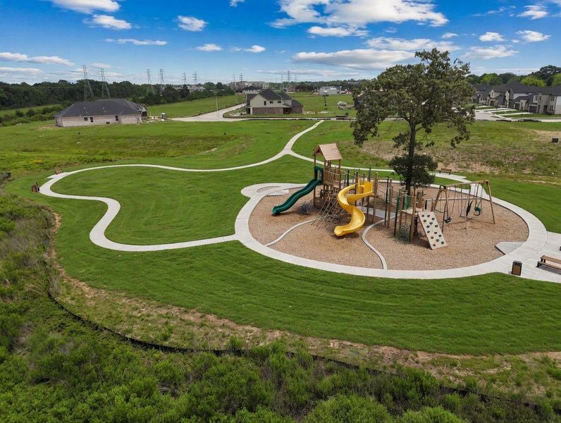 Community playground with swings, slides, and a shaded seating area surrounded by green space