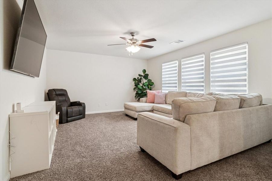 Carpeted living area featuring a ceiling fan and baseboards Carpeted living area featuring a ceiling fan and baseboards