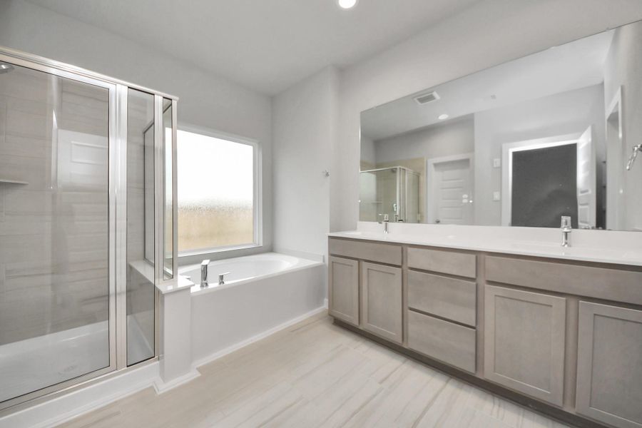 Escape to a spa-like oasis in this primary bathroom. Enjoy a walk-in showerwith tile surround, a separate garden tub with custom detailing, and an elegantvanity featuring light countertops, modern hardware, and beautiful vanity lights.Experience luxury and relaxation in every detail. Sample photo of completed home with similar floor plan. Actual colors and selections may vary. Escape to a spa-like oasis in this primary bathroom. Enjoy a walk-in showerwith tile surround, a separate garden tub with custom detailing, and an elegantvanity featuring light countertops, modern hardware, and beautiful vanity lights.Experience luxury and relaxation in every detail. Sample photo of completed home with similar floor plan. Actual colors and selections may vary.